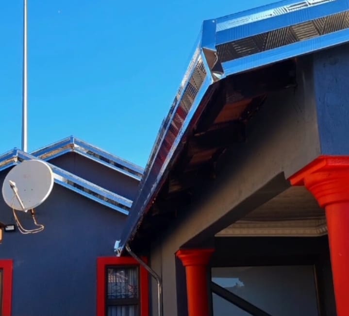 Galvanised gutters fitted to a roof edge against a blue sky